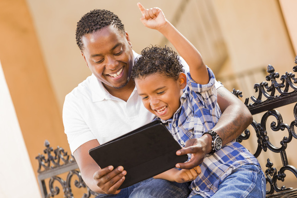 Padre e hijo de raza mixta usando tableta de computadora Touch Pad
 - Foto, imagen