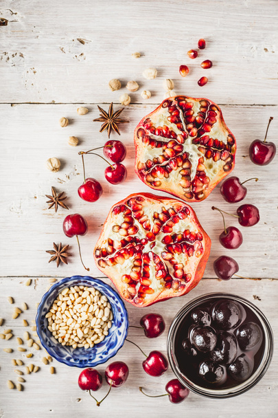 Still life with pomegranate , cherry and spices on the white wooden table. Concept of oriental fruits vertical - Foto, immagini