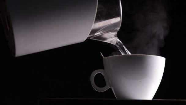 Pouring boiling water in cup on black background - Video