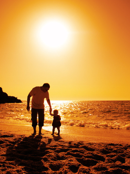 Vater und Tochter spielen am Strand bei Sonnenuntergang - Foto, Bild