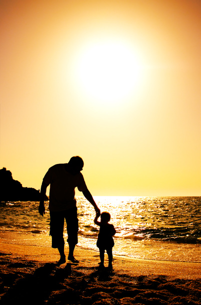 Батько і дочка грають на пляжі на заході сонця
 - Фото, зображення