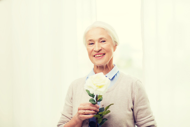 happy senior woman with rose flower at home - Foto, Bild
