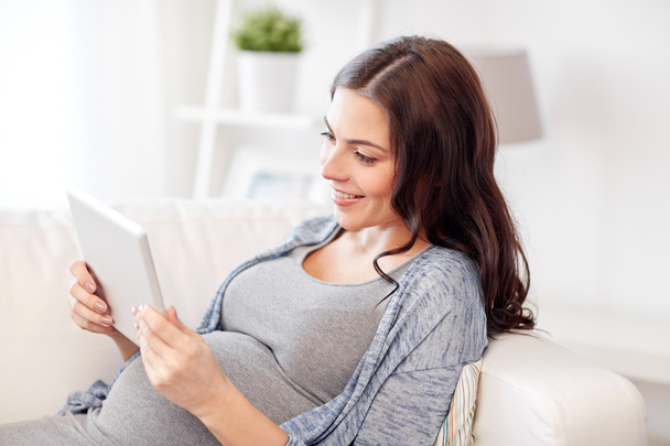 happy pregnant woman with tablet pc at home - 写真・画像
