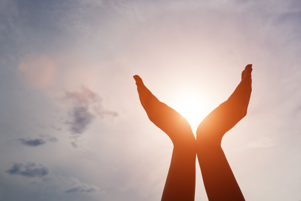Nostakaa kätenne auringonlaskun aikaan. Hengellisyyden, hyvinvoinnin ja positiivisen energian käsite
 - Valokuva, kuva