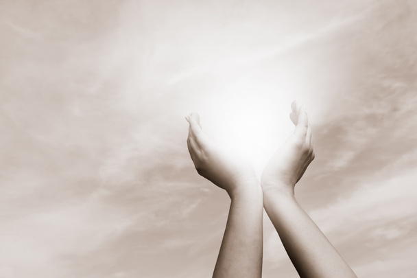Aan de orde gesteld handen vangen van zon op bewolkte hemel. Concept van spiritualiteit, welzijn, positieve energie - Foto, afbeelding