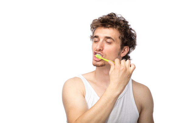 curly guy brushing his teeth - Фото, изображение