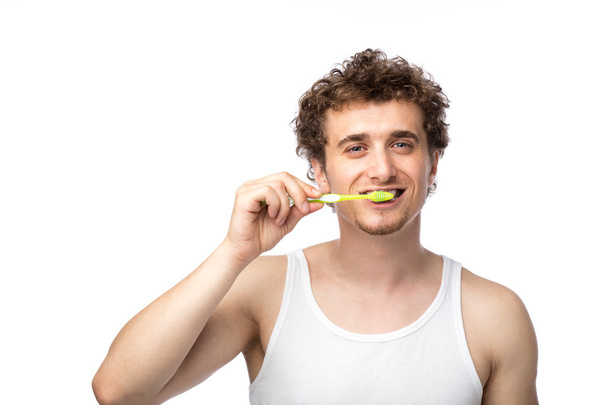 curly guy brushing his teeth - Fotó, kép