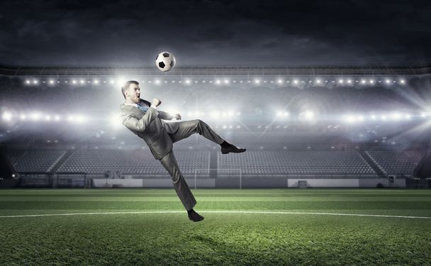 Businessman kicking ball . Mixed media - Foto, imagen