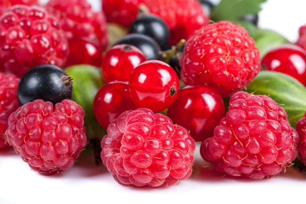 A mixture of ripe juicy fruits and berries on a white background. Raspberries, currants, gooseberries close-up. Beautiful fruit background - Photo, Image