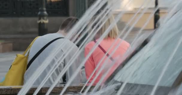 Happy affectionate couple cooling off near a water fountain in the city - Footage, Video