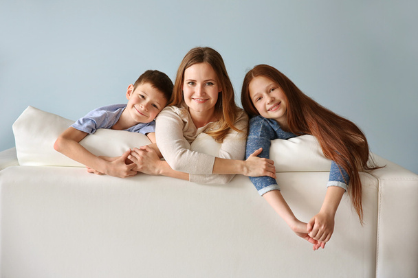 Smiling mother with children on sofa - Foto, imagen
