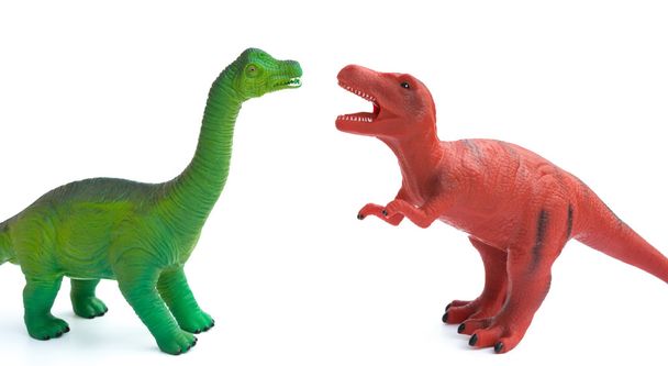 зеленый брахиозавр и красные игрушки тираннозавра на белом фоне
 - Фото, изображение