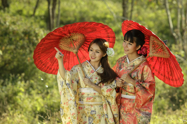 Ζευγάρι Ασίας γυναίκες φορώντας το παραδοσιακό ιαπωνικό κιμονό και κόκκινο u - Φωτογραφία, εικόνα