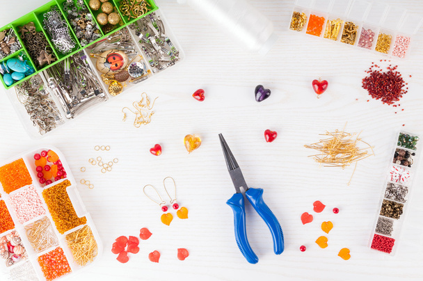 Making handmade jewelry. Boxes with beads, pliers, threads, equipment and accessories for handmade on wooden table. Process of needlework - 写真・画像