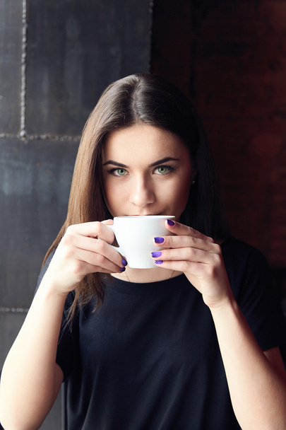 Chica joven bebiendo té en la cafetería y sosteniendo la taza
 - Foto, Imagen