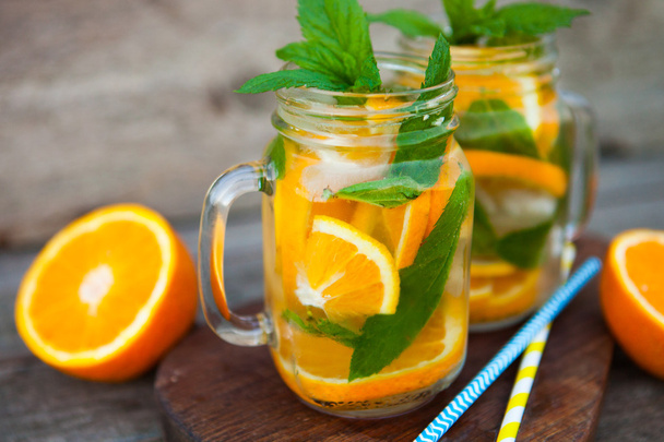 Fresh cocktail with orange, mint and ice, selective focus - Foto, afbeelding
