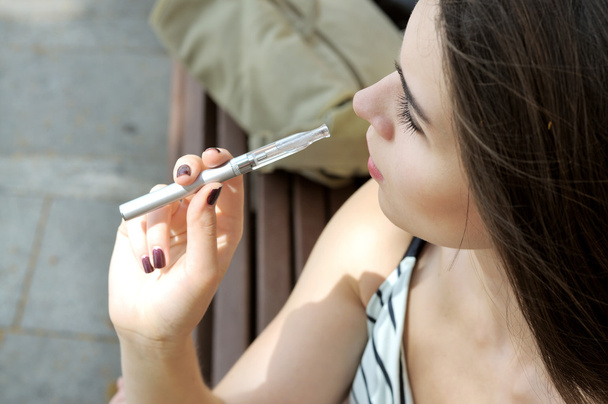 Girl smokes an electronic cigarette - Фото, зображення