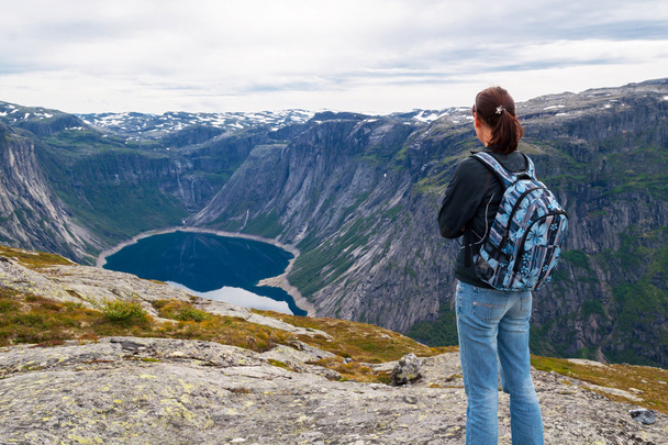 woman looking at the lake in the mountains, Norway. Path to Trolltunga or Troll tongue - Fotografie, Obrázek