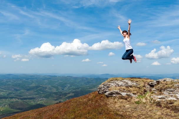 mujer joven saltando sobre un fondo de montañas
 - Foto, imagen