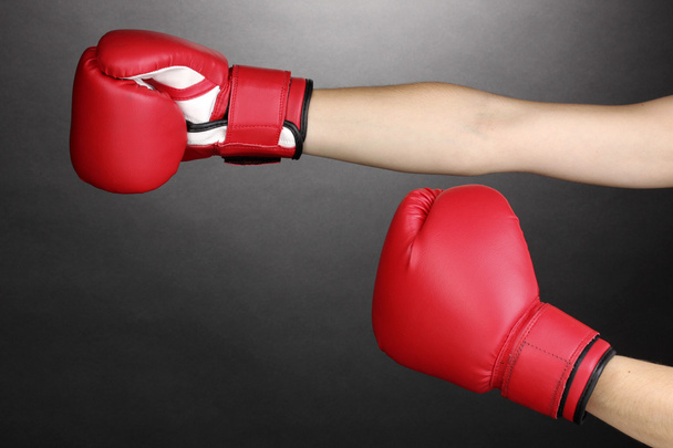 Red boxing gloves on hands on grey background - 写真・画像