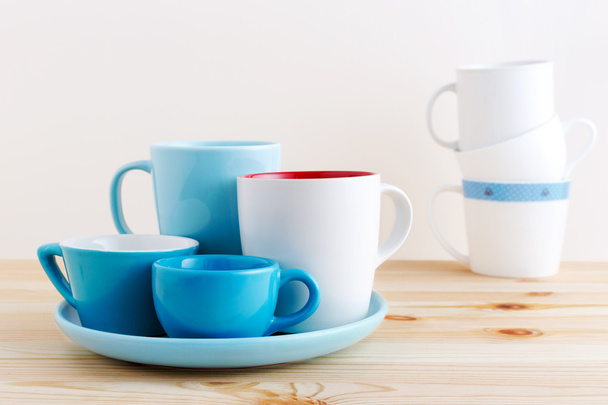 Синие чашки и белая кружка на деревянном столе
 - Фото, изображение