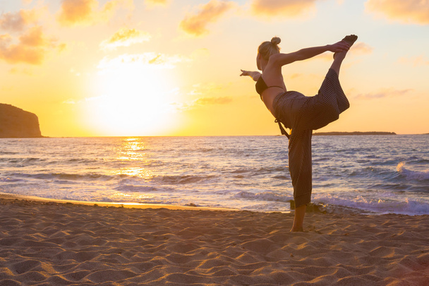 Woman practicing yoga on sea beach at sunset. - Photo, Image