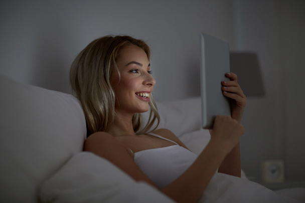young woman with tablet pc in bed at home bedroom - Fotó, kép