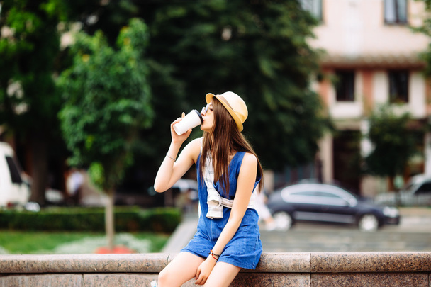 Красива дівчина з вийманням кави в міському сквері
 - Фото, зображення