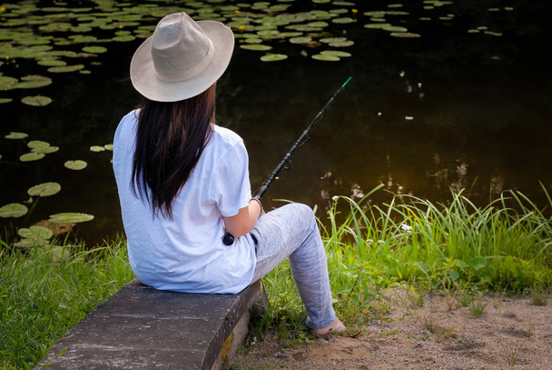 Young woman fishing in pond in summer - Photo, Image
