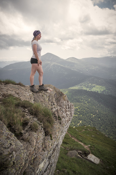 Ragazza escursionista in piedi sulla scogliera e guardando le montagne
.  - Foto, immagini