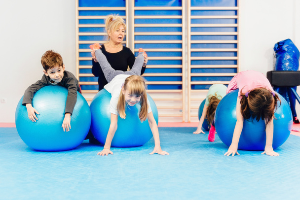 Grupo de niños haciendo ejercicio con pelotas de fitness
 - Foto, imagen