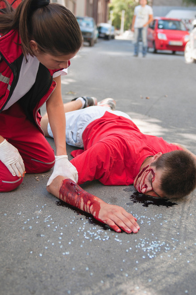 Paramédico con víctima de accidente de coche en la calle
 - Foto, Imagen