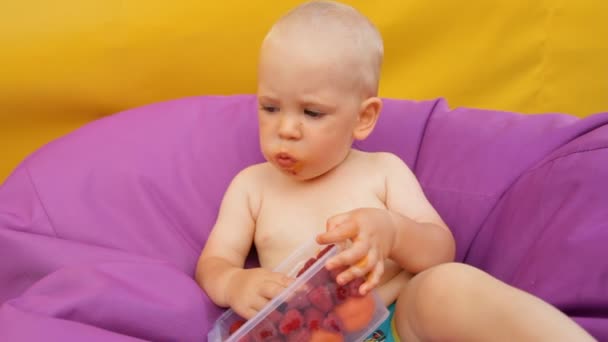 Gyermek étkezési gyümölcs fekve egy fotelben - Felvétel, videó