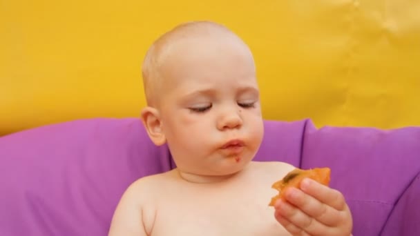 Gyermek étkezési gyümölcs fekve egy fotelben - Felvétel, videó