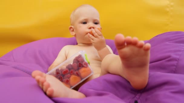 Niño comiendo fruta acostado en una silla fácil
 - Imágenes, Vídeo
