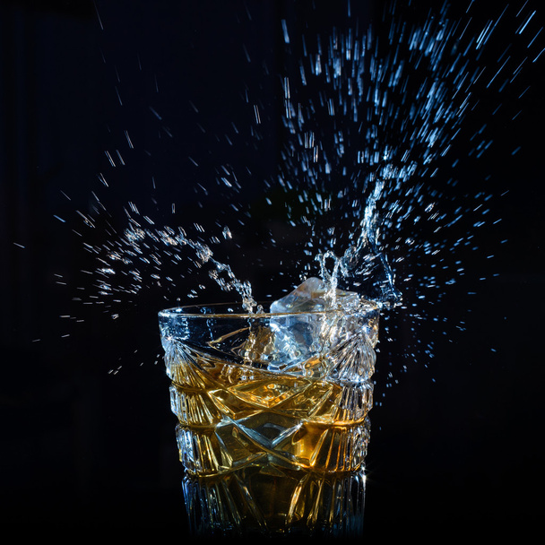 Whisky salpicado de los cubitos de hielo que caen
 - Foto, imagen