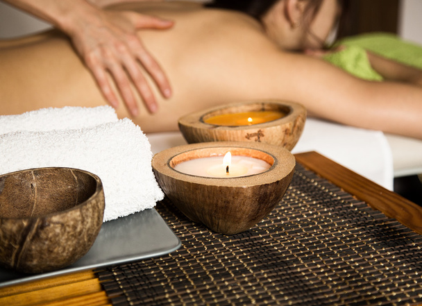 Young woman receiving a back massage in the spa salon. close-up of a candle and towels - Foto, imagen