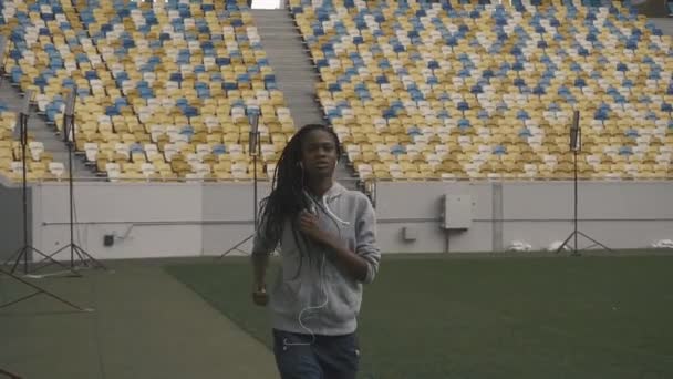 Молода сексуальна афроамериканка підходить жінка слухає музику і бігає на фоні міського стадіону
 - Кадри, відео