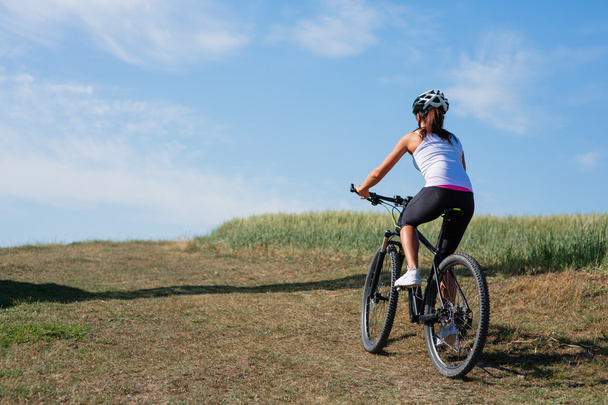 Jovem senhora com bicicleta em um prado de primavera
 - Foto, Imagem