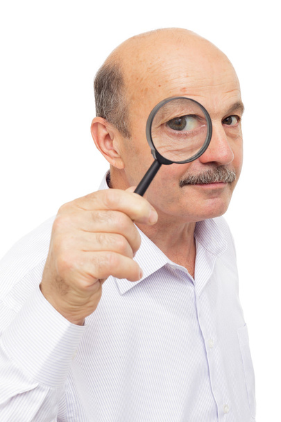 elderly man looks at something through a magnifying glass. - Фото, зображення
