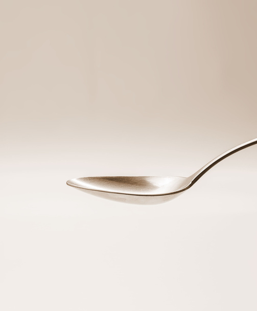 Empty tablespoon of metal on sepia background - Фото, изображение