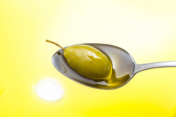 Зелена оливкова олія в повній олійній ложці, вид зверху
 - Фото, зображення