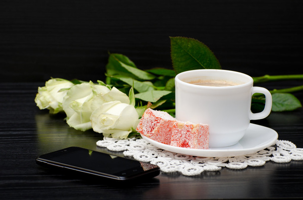 Widok z boku Kawa kubek z mlekiem, orientalnych słodyczy. Smartphone, białe róże - Zdjęcie, obraz