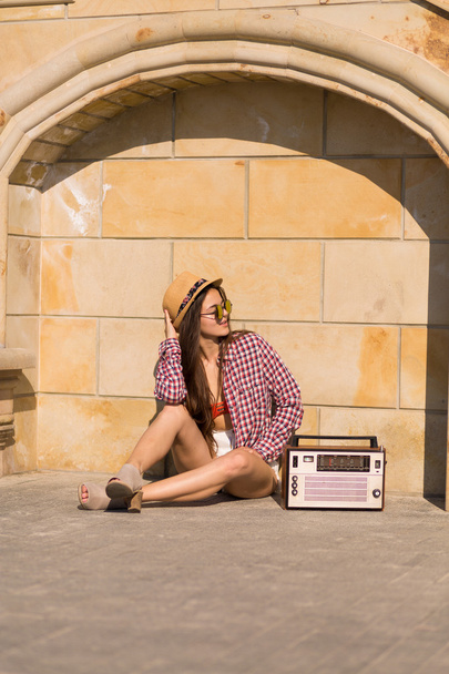 Beautiful young boho woman with a retro stereo sitting on a stre - Photo, image