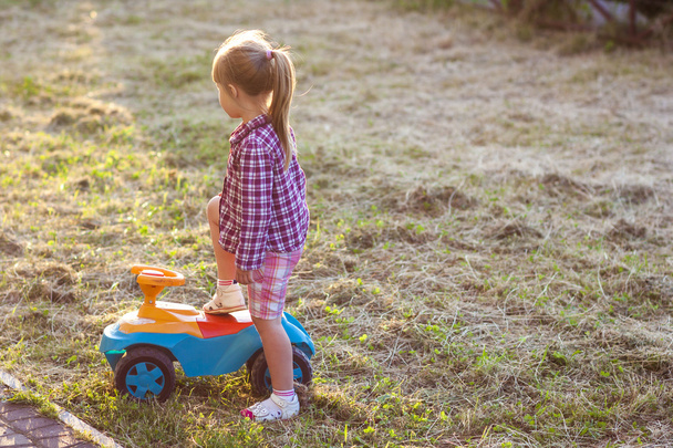 Little cute girl outdoors with a toy car on a sunny day - Photo, Image