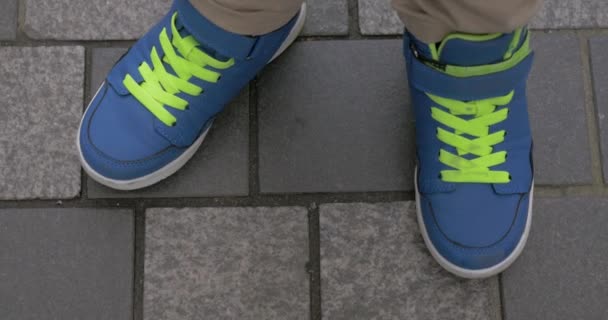 Παιδί μέτρα σε μπλε εκπαιδευτές σε πλακόστρωτο πεζοδρόμιο - Πλάνα, βίντεο