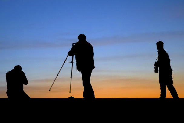 Silueta de salida del sol de fotógrafos disparando
 - Foto, Imagen