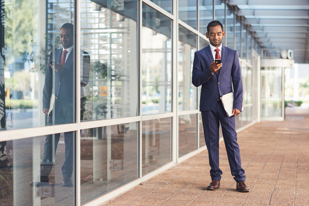 businessman texting on cellphone in front of office - Photo, Image