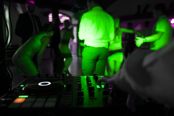 Dj mezcla la pista en el club nocturno en la fiesta con gente bailando en un fondo borroso
 - Foto, imagen