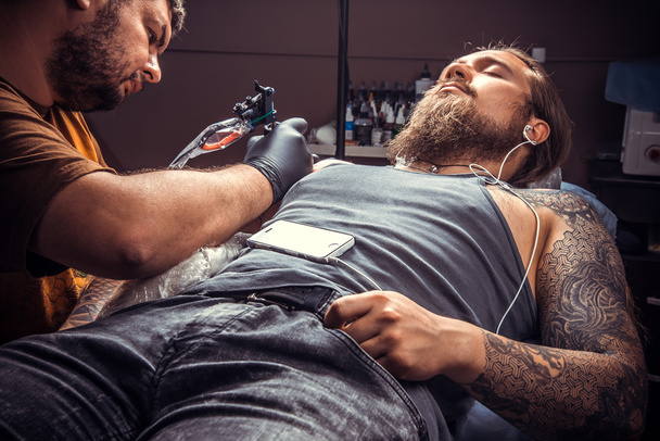 Especialista en tatuajes haciendo tatuaje en salón de tatuajes
 - Foto, Imagen
